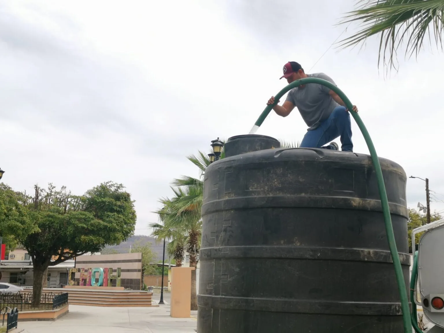 Persona llenando un tinaco con agua de pipa en Choix, Sinaloa.