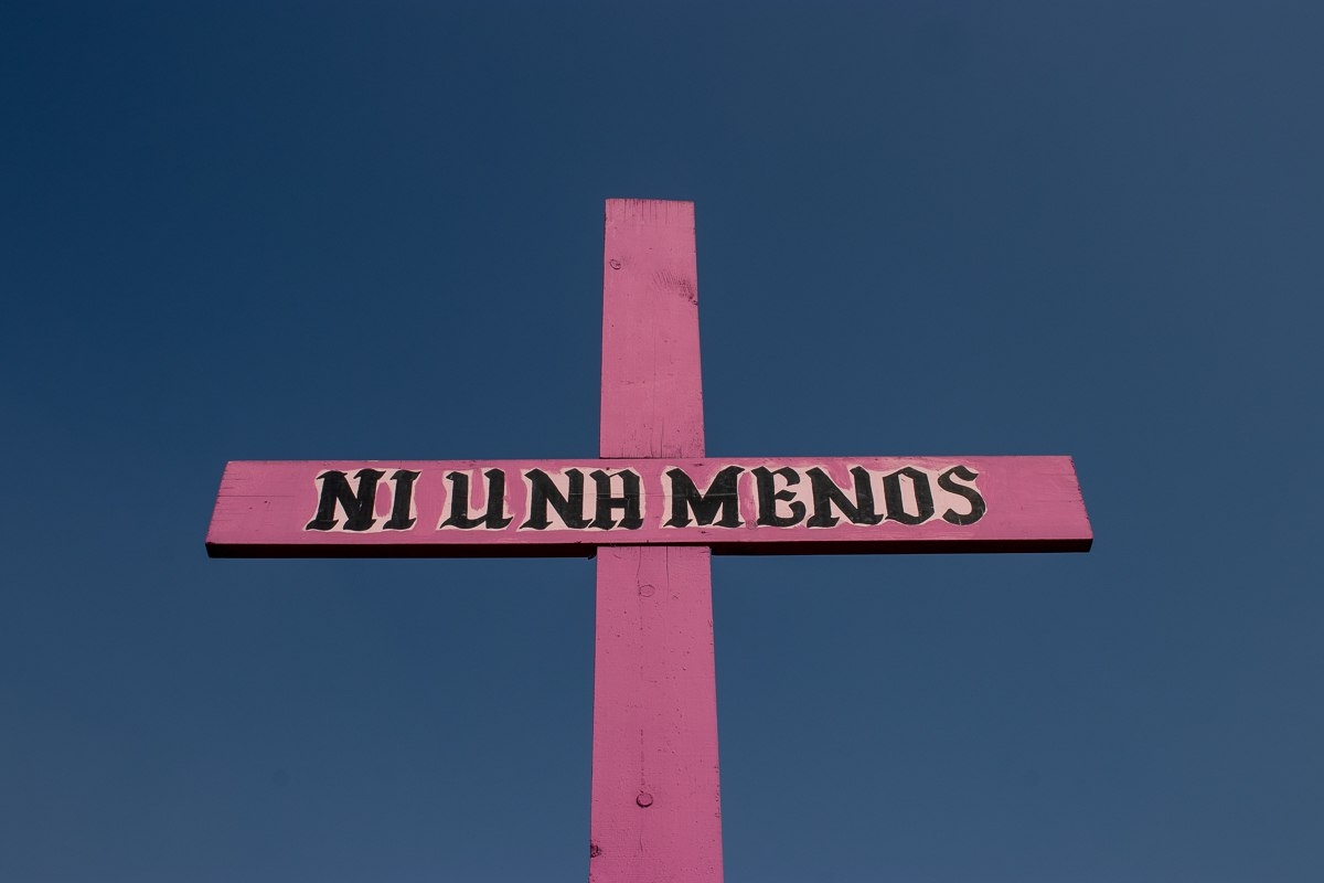 Cruz rosa con la frase “Ni una menos” sobre fondo azul, símbolo utilizado en coberturas sobre feminicidio y violencia contra las mujeres.